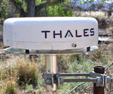 Thales satellite dish antenna in an outdoor setting with trees and grass.